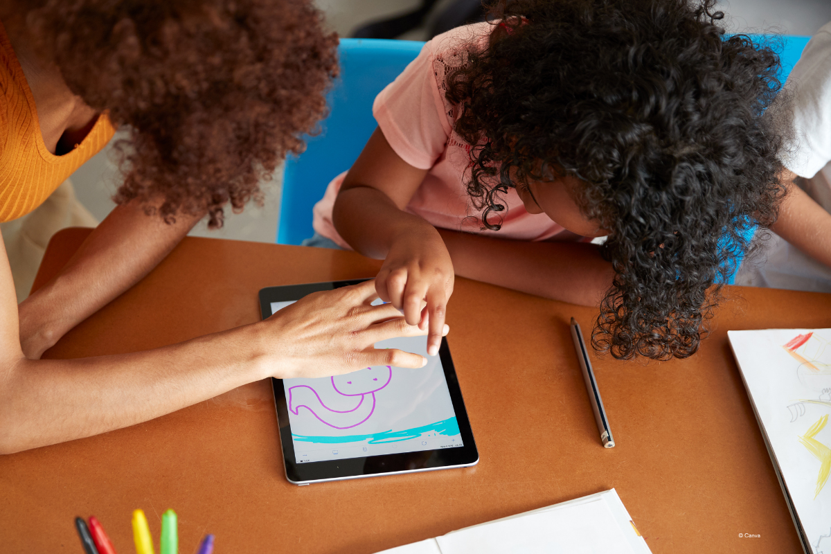 Eine ältere Person, die einer jüngeren Person etwas auf einem Tablet zeigt.