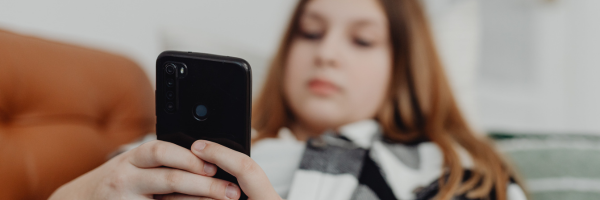 Eine Person, die auf dem Sofa liegt und auf ihr Smartphone schaut.